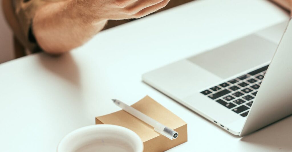 Person interacting with smartphone at tidy desk with laptop and coffee mug, showcasing modern technology.